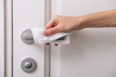 Antiseptik ıslak mendil ve eldivenle kapı kolları temizleniyor. Ev kapısı bağlantısını temizlemek için havlu kullanan kadın eli. Hastane ve halka açık alanlarda korona virüsüne karşı yüzeylerin sterilize edilmesi