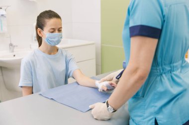 İlk yardım için bileğine dolanmış bir doktor. Hastaların ellerine bandaj uygulaması, ilk yardım konseptleri ve bilek yaralanması tedavisi. Hastanın elinde tıbbi bandaj var. Bilek ağrısı.