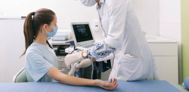 Doktor eline ultrason yapıyor. Yakın plan. Doktor ultrason sonuçlarını hastaya gösterir. Tıbbi ultrason taraması. Kas gevşemesi için botoks enjeksiyonunun rehabilitasyon uygulaması