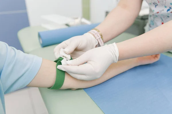 Sto facendo un esame del sangue da una vena nella sala di trattamento. Infermiera che punta una siringa con un ago nella mano del paziente. Tampone premuto contro il sito di iniezione durante la donazione di sangue. Tubo con sangue — Foto Stock