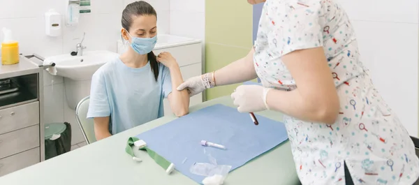 Een bloedtest laten doen vanuit een ader in de behandelkamer. Zuster prikt een injectiespuit met een naald in de patiëntenhand. Een wattenstaafje dat tijdens de bloeddonatie tegen de injectieplaats werd gedrukt. Buis met bloed — Stockfoto