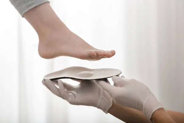 白い背景に整形外科のインソール.ゴム手袋の手は整形外科のインソールを保持します。足のケア、足の快適さ。整形外科医は医療機器をテストします。平らな足の修正 — ストック写真