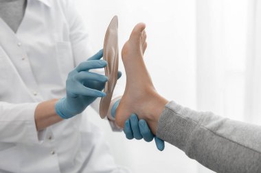 Doktor elleri ortopedik tabanı tutuyor. Ortopedist tıbbi cihazı test ediyor. Beyaz arka planda ortopedik tabanlar. Ayak bakımı, ayaklara iyi gelir. Düztaban ve ayağın tedavisi ve önlenmesi