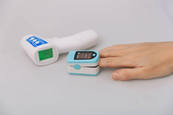Pulse oximeter and thermometer gun on white background. Infrared isometric thermometer gun to check body temperature for virus symptoms. Measuring oxygen saturation, pulse rate and oxygen levels — Stock Photo, Image