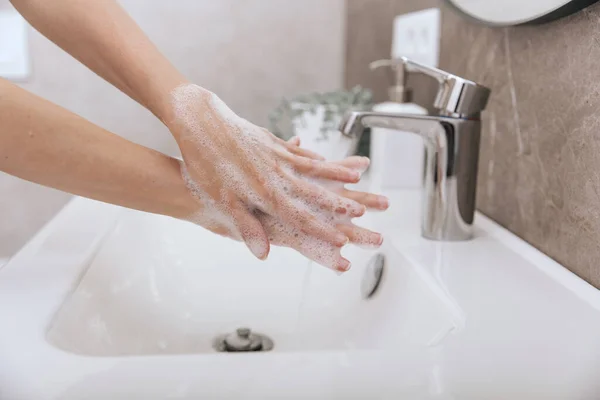 Lavarse las manos bajo el grifo de agua corriente. Concepto de higiene detalle de la mano. Lavarse las manos frotándose con jabón para prevenir el virus de la corona, higiene para dejar de propagar el virus de la corona en el baño público — Foto de Stock