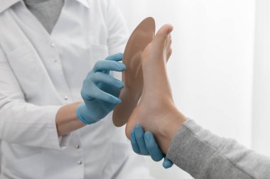 Doktor elleri ortopedik tabanı tutuyor. Ortopedist tıbbi cihazı test ediyor. Beyaz arka planda ortopedik tabanlar. Ayak bakımı, ayaklara iyi gelir. Düztaban ve ayağın tedavisi ve önlenmesi