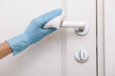 Siyah kapı kollarını antiseptik beyaz mendil ve dezenfektanla temizliyorum. Hastane ve kamusal alanlarda korona virüsüne karşı korunma yüzeylerini sterilize edin. Kadın eli temizlik için havlu kullanıyor.