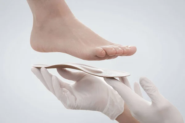 Orthopedic insole isolated on a white background. Hands in rubber gloves hold an orthopedic insole. Foot care, comfort for the feet. Doctor orthopedist tests the medical device. Flat feet correction
