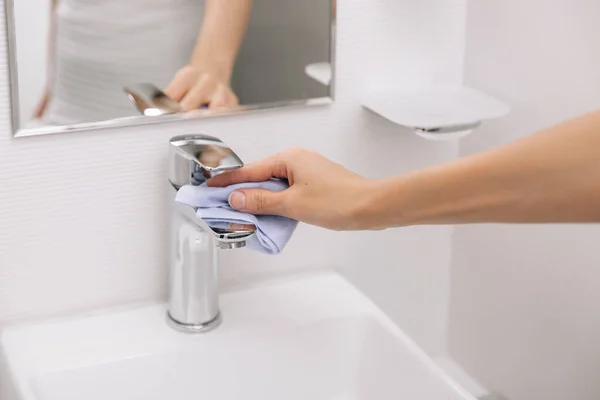 Reinigung des Spülwasserhahns mit einem Mikrofasertuch. Prävention von Oberflächen in Krankenhäusern und öffentlichen Räumen gegen Coronavirus sanieren. Frauenhand mit Feuchttüchern. Reinigung des Badezimmers — Stockfoto