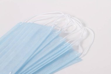Mavi tek kullanımlık cerrahi maske. Koronavirüse karşı kulak bantlı koruyucu maske ve beyaz arka planda izole edilmiş bakteriler. Sağlık hizmetleri tıbbi hijyen kavramı