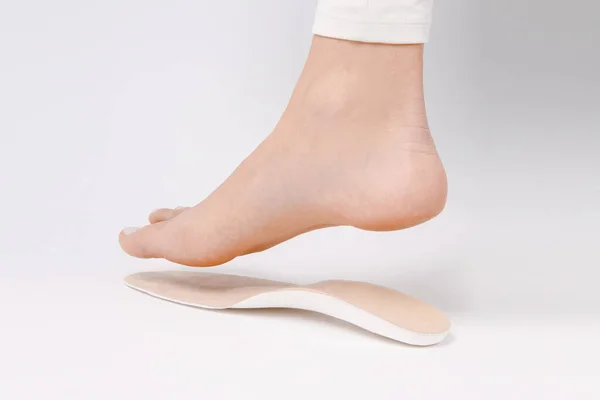 Medical insoles. Isolated orthopedic insoles on a white background. Foot care. Insole cutaway layers. Leg hanging over the insole. Treatment and prevention of flat feet and foot diseases — Stock Photo, Image
