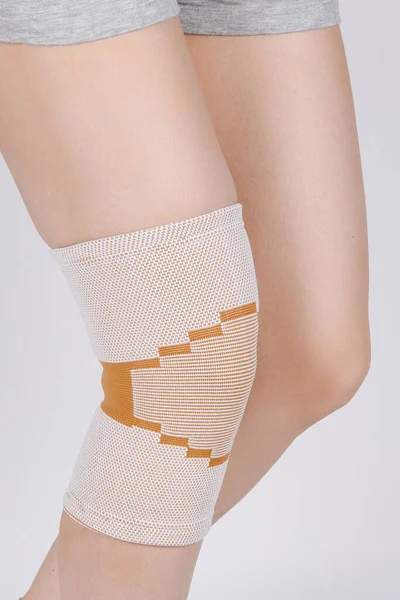 Knee Support Brace on leg isolated on white background. Elastic orthopedic orthosis. Anatomic braces for knee fixation, injuries and pain. Protective knee joint bandage sleeve. Trauma, rehabilitation