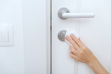 Antiseptik ıslak mendil ve eldivenle kapı kolları temizleniyor. Hastane ve kamusal alanlarda korona virüsüne karşı korunma yüzeylerini sterilize edin. Kadın eli temizlik için havlu kullanıyor.