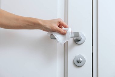 Antiseptik ıslak mendil ve eldivenle kapı kolları temizleniyor. Ev kapısı bağlantısını temizlemek için havlu kullanan kadın eli. Hastane ve halka açık alanlarda korona virüsüne karşı yüzeylerin sterilize edilmesi