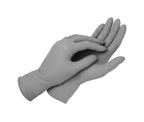 Медицинские перчатки. Две серые хирургические перчатки на белом фоне с руками. Изготовление резиновых перчаток, человеческая рука в латексной перчатке. Врач или медсестра надевают защитные перчатки — стоковое фото