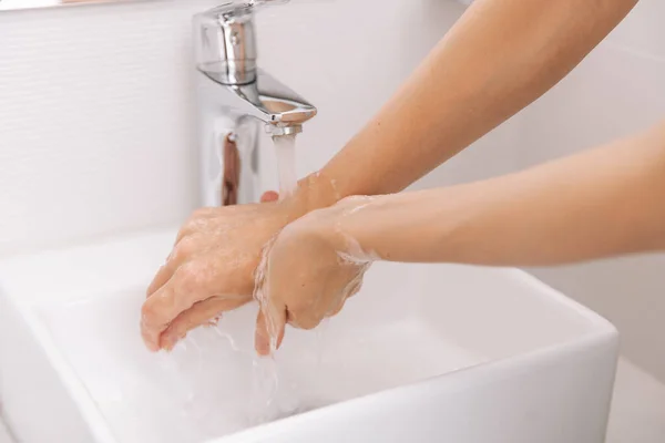 Washing hands under the flowing water tap. Hygiene concept hand detail. Washing hands rubbing with soap for corona virus prevention, hygiene to stop spreading corona virus in or public wash room — Stock Photo, Image