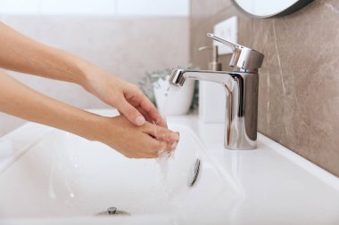 Akan su musluğunun altında ellerini yıkamak. Hijyen konsepti el detayı. Corona virüsünün önlenmesi için sabunla ellerini ovuşturmak, korona virüsünü halka yaymayı durdurmak için hijyen. Ya da umumi tuvalette.