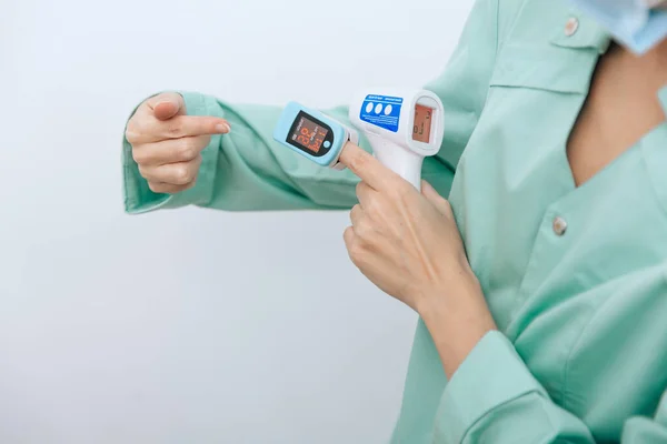 Temperature measurement gun in doctor hands. Close-up shot of doctor wearing protective surgical mask ready to use infrared isometric thermometer gun to check body temperature for virus symptoms — Stock Photo, Image