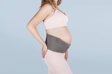 Hamilelik öncesi hamilelik kemeri takmış hamile bir kadın. Ortopedik karın desteği bel, sırt, karın bandı. Hamilelik için karın korsesi ya da bant. Yatay web pankartı. Hamile modelin gövdesi