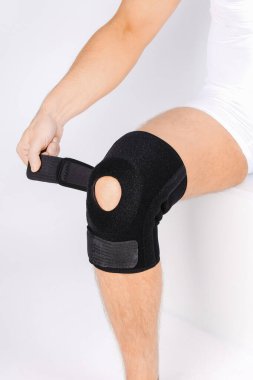 Diz Destek Kolu beyaz arka planda izole edilmiş bir bacak üzerinde. Elastik ortopedik ortopedi. Diz saplantısı, yaralanma ve ağrı için anatomik destek. Koruyucu diz eklemi bandaj kolu. Travma, rehabilitasyon.