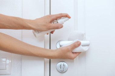 Siyah kapı kollarını antiseptik ıslak mendil ve dezenfektanla temizliyorum. Hastane ve kamusal alanlarda korona virüsüne karşı korunma yüzeylerini sterilize edin. Kadın eli temizlik için havlu kullanıyor.