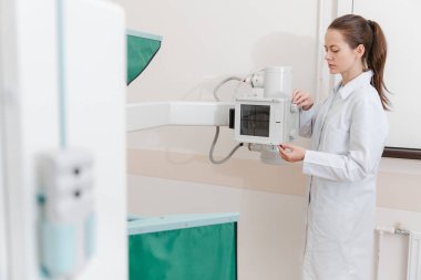 Hastane Radyoloji Odası. Florografi için röntgen makinesi. Doktor radyoloji uzmanı röntgen cihazını radyografi için ayarlıyor. Tıbbi ekipman. Klinikte göğüs, kalp ya da akciğerler taranıyor