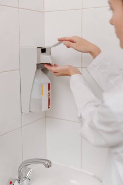 Beyaz üniformalı doktor ellerini dezenfekte ediyor. Cerrah el yıkama hastane konsepti. Hemşire ellerini dezenfeksiyon için dezenfektan, şeker ya da alkol çözeltisi ile yıkıyor.