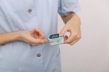 Nabız oksimetresi, beyaza izole edilmiş bir doktorun eliyle. Oksijen doygunluğunu, nabız hızını ve oksijen seviyesini ölçüyorum. Kişilerin oksijen doygunluğunu ölçmek için taşınabilir dijital aygıt kavramı