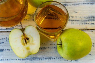 Ahşap zemin üzerinde elma suyu olan yeşil elma ve sürahi.