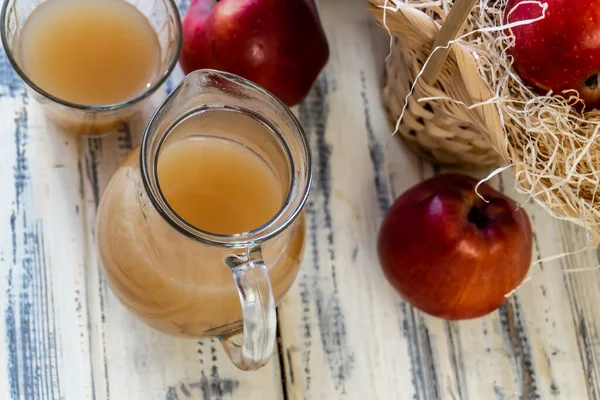Rote Äpfel Korb Und Apfelsaft Krug Auf Einem Holztisch — Stockfoto