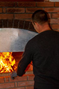 Adam barbekü yapıyor, fırında kebap pişiriyor.