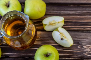 Ahşap zemin üzerinde elma suyu olan yeşil elma ve sürahi.