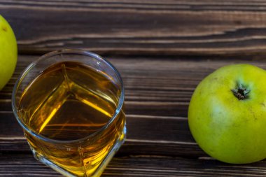 Ahşap zemin üzerinde elma suyu olan yeşil elma ve bardak.