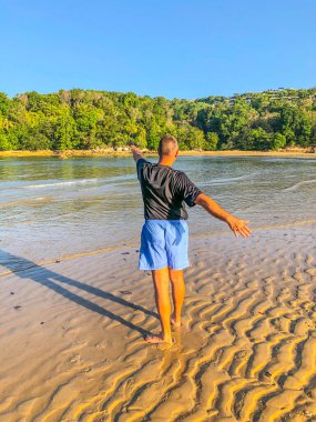 Bir adam spor yapmaya gider, deniz kıyısında egzersiz yapar.