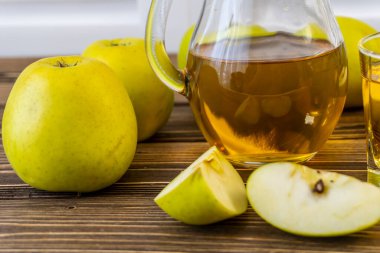 Ahşap zemin üzerinde elma suyu olan yeşil elma ve sürahi.