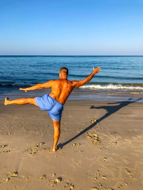 Bir adam spor yapmaya gider, deniz kıyısında egzersiz yapar.