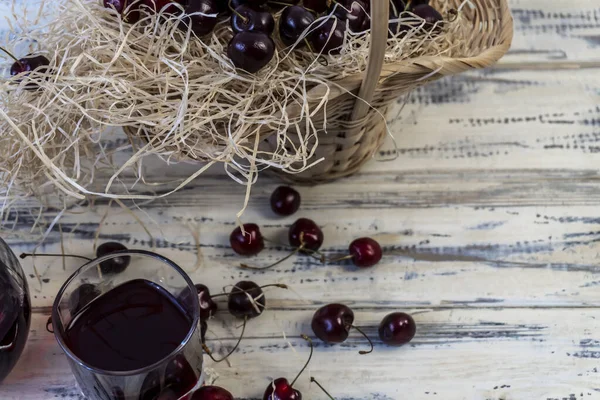 樱桃和樱桃汁或葡萄酒放在木制桌子上 酒壶和杯子里有果汁 篮子里有樱桃 — 图库照片