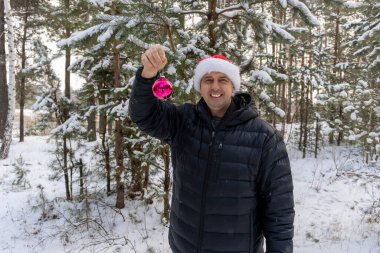 Noel Baba şapkalı bir adam kışın ormanda Noel balosu düzenliyor.
