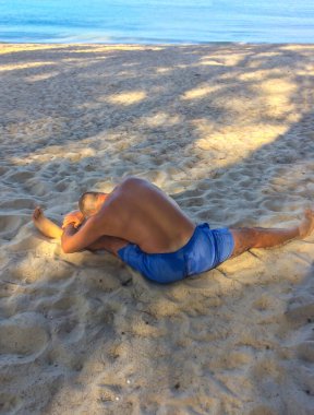 Bir adam spor yapmaya gider, deniz kıyısında egzersiz yapar.