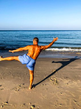 Bir adam spor yapmaya gider, deniz kıyısında egzersiz yapar.