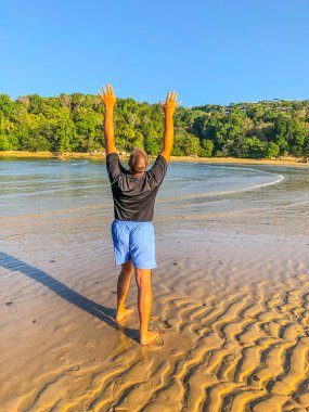 Bir adam spor yapmaya gider, deniz kıyısında egzersiz yapar.