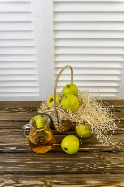 Yeşil elma, elmalı sepet ve ahşap arka planda elma suyu.