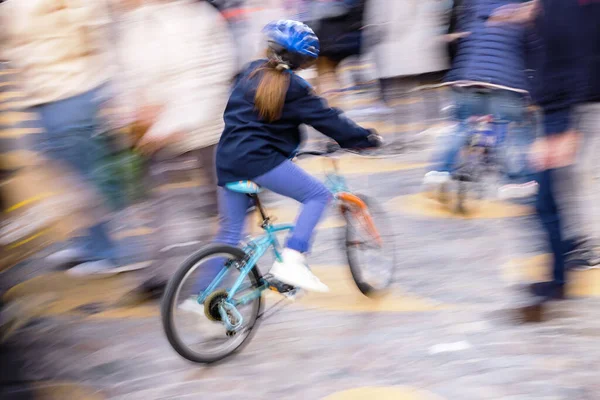 一个年轻姑娘骑着自行车在人群中走来走去的画面模糊了 — 图库照片
