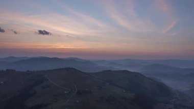 Zaman ayarlı. Mavi sisli dağların üzerinde turuncu ve pembe bulutlarla güzel renkli bir gün doğumu.