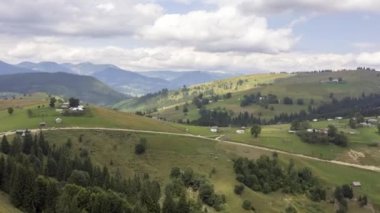 Dağ manzarasının zamanlaması beyaz, hızlı hareket eden bulutlar, yeşil alanlar ve mavi dağlarla