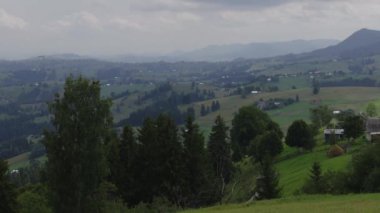 Dağ manzarasının zamanlaması beyaz, hızlı hareket eden bulutlar, yeşil alanlar ve mavi dağlarla