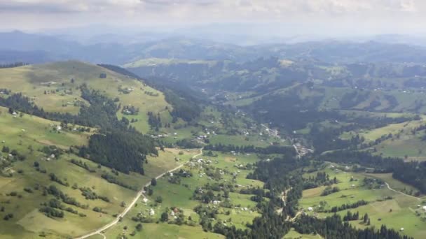 タイムラプスだ ドリー ズーム 山の緑の芝生と小さな村の上を飛ぶ — ストック動画