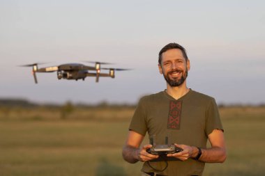 Drone 'la oynayan sakallı bir adam. Pilot bir İHA uçuruyor. İnsansız hava aracı kullanımı, pilotluk ve medya çalışmaları