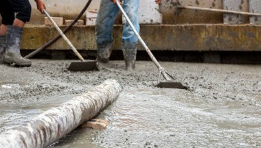 Profesyonel işçiler ağır sanayide inşaat sahalarında beton döşeme yapıyorlar..