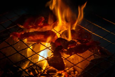 Geceleri ızgarada domuz eti pişirirken duman ve ateş çıkıyor.
